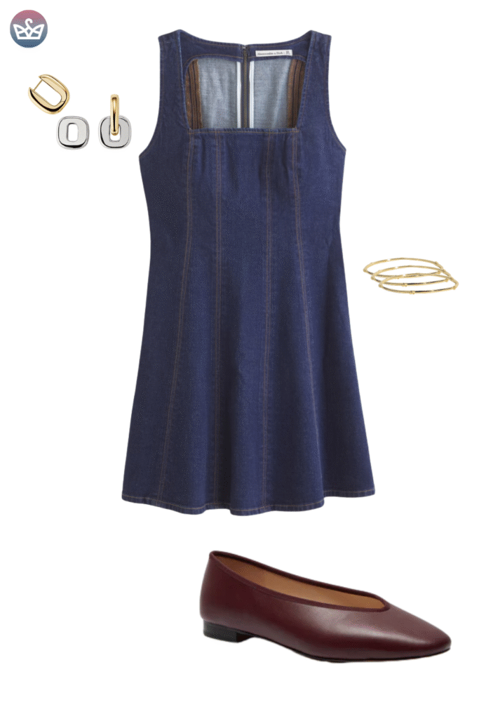 Classic denim fall outfit featuring a square neck dark wash denim pinafore dress layered over a simple top not visible and paired with gold hoop earrings and thin bracelets The key footwear is a sleek dark leather ballet flat ranging from deep brown to burgundy A simple and fashionable autumn look prioritizing comfortable flat footwear