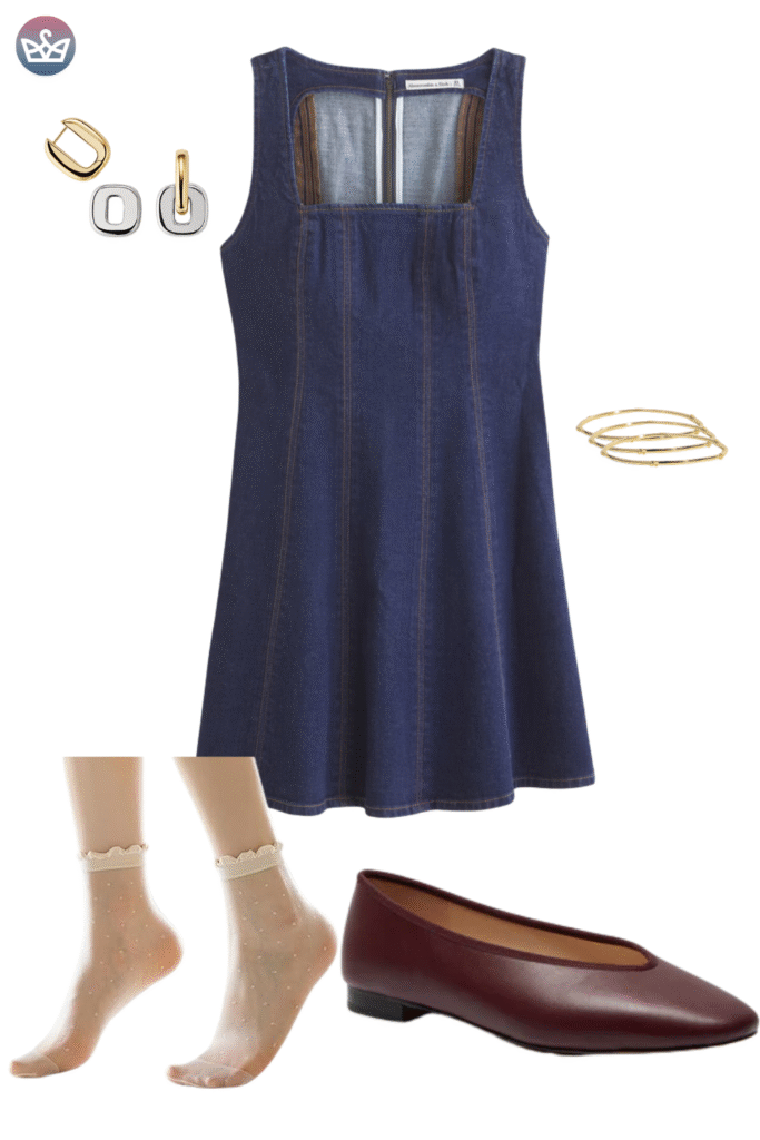 Classic denim fall outfit featuring a square neck dark wash denim pinafore dress layered over a simple top not visible and paired with gold hoop earrings and thin bracelets The key footwear is a sleek dark leather ballet flat ranging from deep brown to burgundy A simple and fashionable autumn look prioritizing comfortable flat footwear