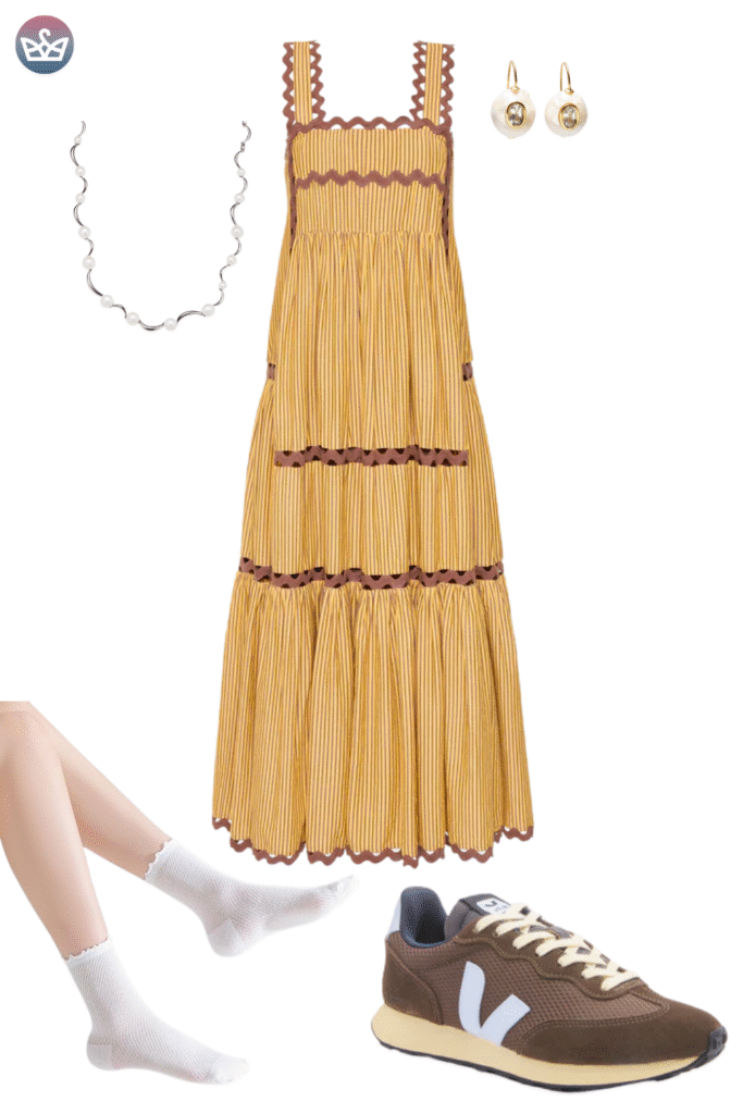 Unique bohemian fall outfit featuring a stunning tiered fringed straw colored maxi dress with subtle white edging Accessorized with simple gold hoop earrings and styled with brown and white retro sneakers and socks This look focuses on bringing comfort footwear to a dramatic dress silhouette for a casual autumn event