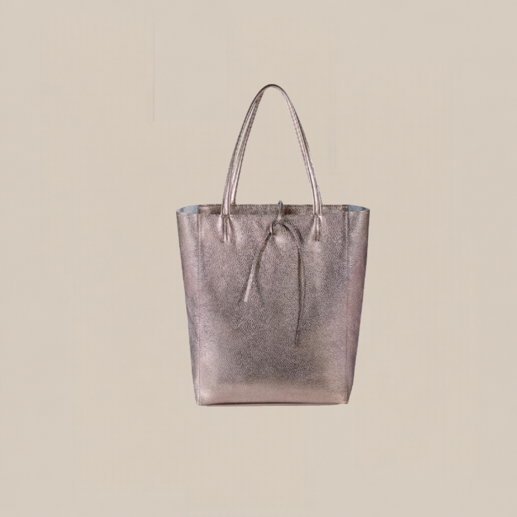 Metallic pink tote bag with two handles on a neutral beige background Tldr winter work outfits are easier with seven closet staples kick crop pants office shoes in the same color a button down a merino sweater a third piece weatherproof boots and a work tote Pair the pants and shoes in one color then build the top half around a button down and a merino sweater with a  adjust my crown